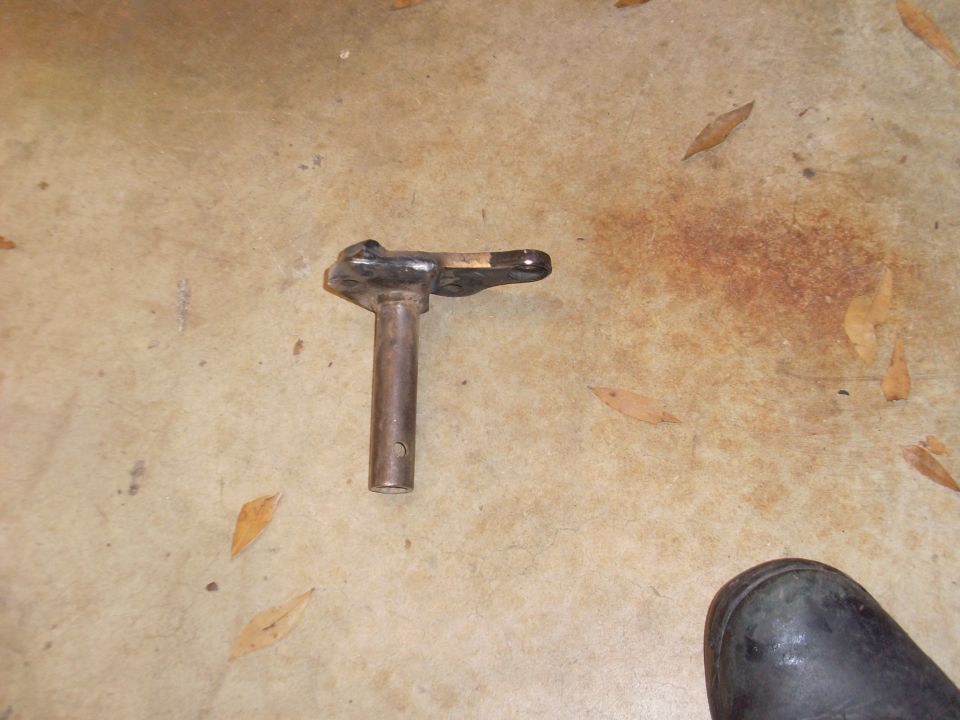 T-shaped welded steel bracket with drilled tube stub lying on a concrete shop floor