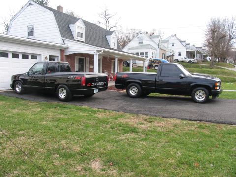 1990 Chevrolet Silverado 1500 - Two black Chevrolet pickup trucks are parked side-by-side in a residential driveway.