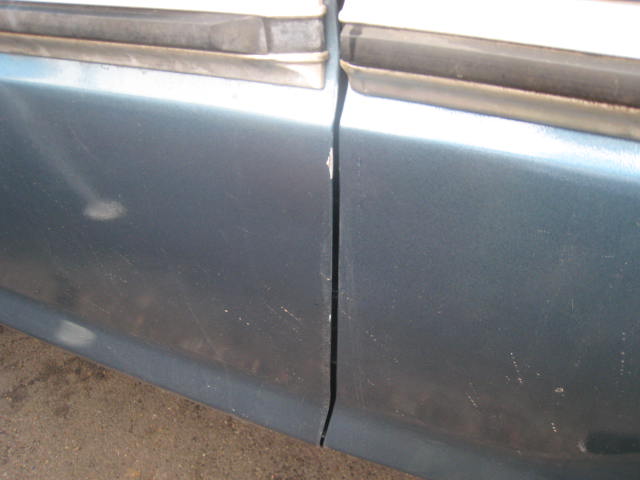 Close-up of a blue-gray car door panel and body seam