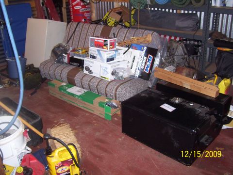 1978 Ford Bronco - A black fuel tank sits on a garage floor next to a couch and various boxes.