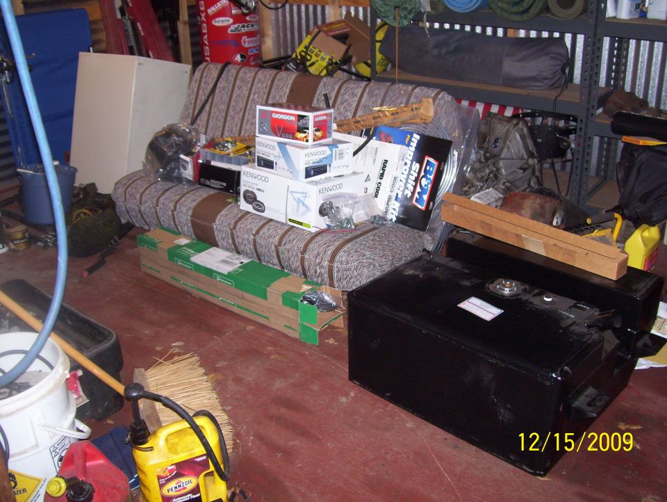 Black rectangular fuel tank with a wooden block on top, seen from a 3/4 front angle