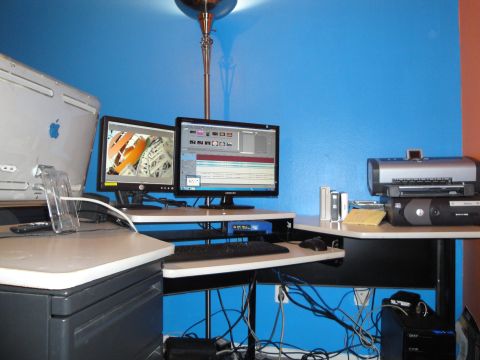 1993 Ford Taurus - A cluttered computer workstation is set up with multiple monitors and peripherals against a blue wall.