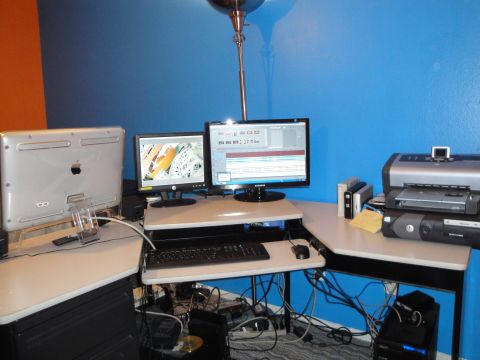 1993 Ford Taurus - A cluttered computer workstation with multiple screens and peripherals is set up against a blue wall.