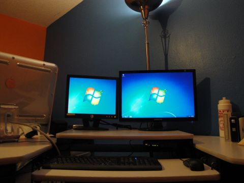 1993 Ford Taurus - A desk setup features two computer monitors displaying the Windows 7 default wallpaper, alongside a keyboard and mouse.