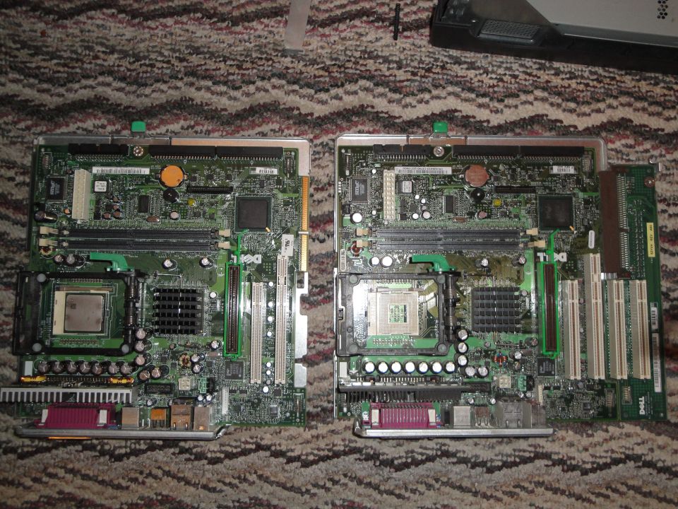 Two Dell computer motherboards laid out on a carpeted surface