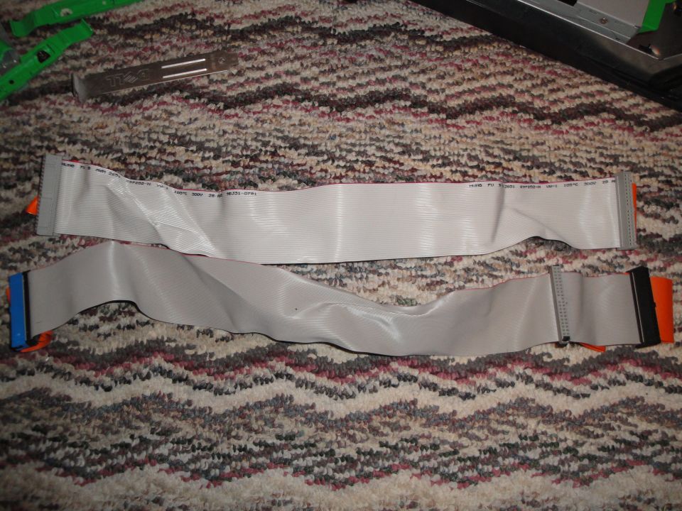 Two IDE ribbon cables with orange and blue connectors on a carpeted surface