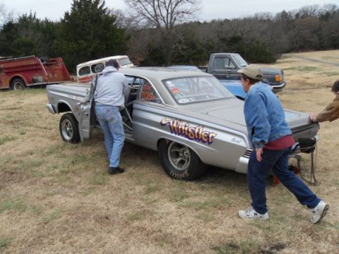 1963 Ford Fairlane - A silver 1963 Ford Fairlane drag car, identified by its 'Whistler' branding, is being pushed by two individuals.