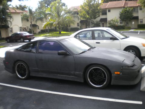 1991 Nissan 240SX - A dark gray 1991 Nissan 240SX is parked in a lot with other vehicles.