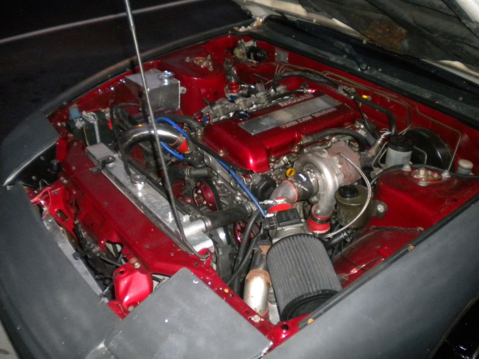 Engine bay with red painted components, turbocharger, and aftermarket air filter