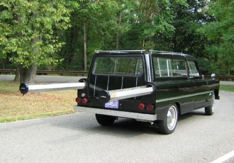 1991 Ford Bronco - Rear three-quarter view of a custom black station wagon with a chrome roof rack, whitewall tires with chrome hubcaps, round taillights and…