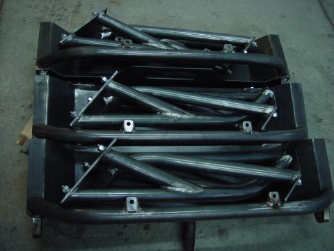 1993 Ford Bronco - Several unfinished metal bumper assemblies are stacked and ready for installation.