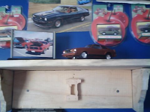 1978 Ford Mustang II - Model of a 1978 Ford Mustang II sits on a wooden shelf, with other car memorabilia in the background.