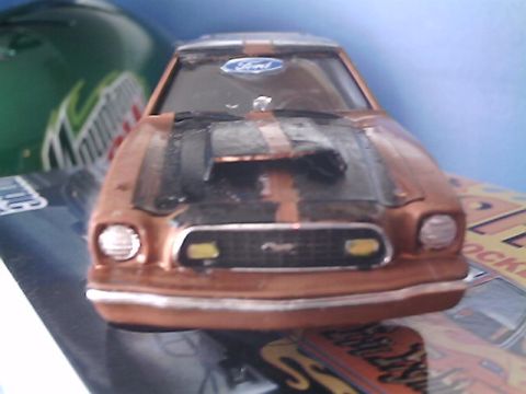 1978 Ford Mustang II - A toy car with a Ford badge on the windshield sits on a surface with other items.