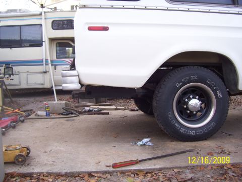 1978 Ford Bronco - A white pickup truck is parked next to an RV, with tools scattered on the ground.