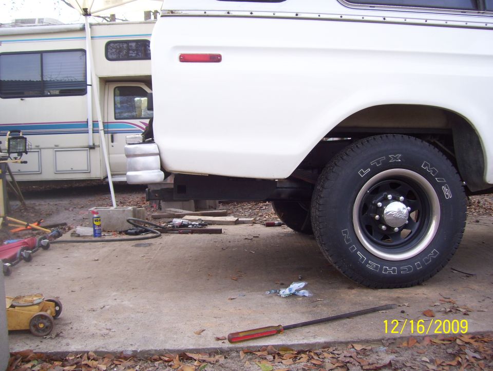 White pickup truck rear quarter panel and tire, parked next to an RV