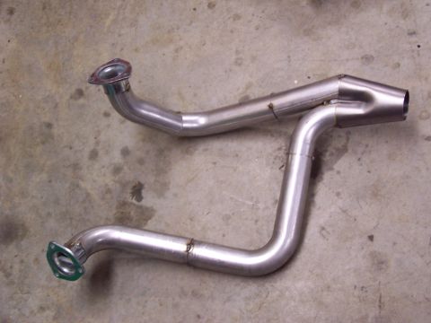 1991 Jeep Comanche - Two shiny metal exhaust pipes with flanges are laid out on a concrete floor.