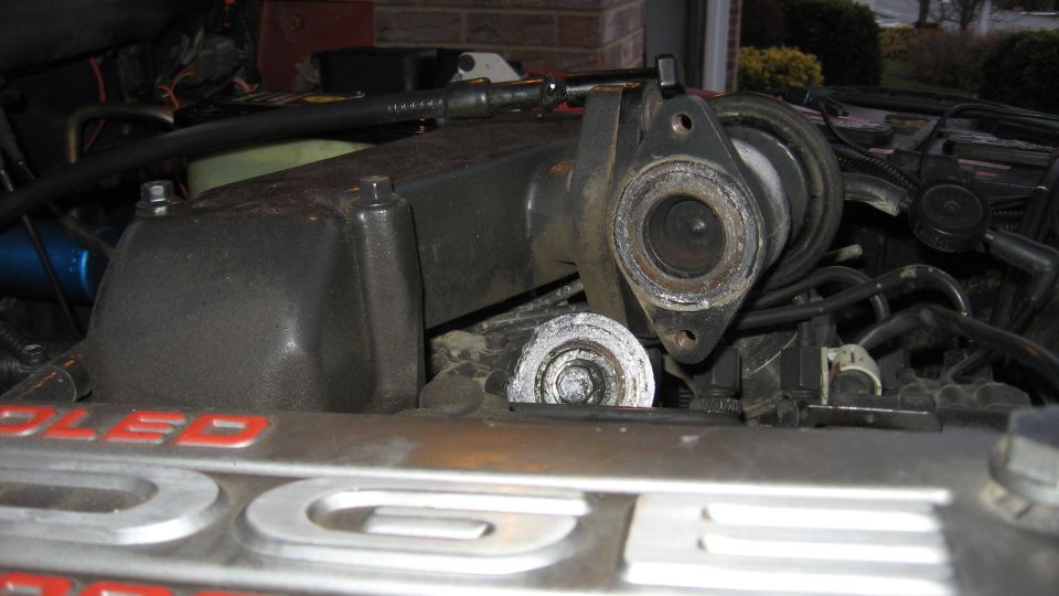 Engine bay with manifold removed, showing internal components and hoses. Text on metal reads 'COOLED'