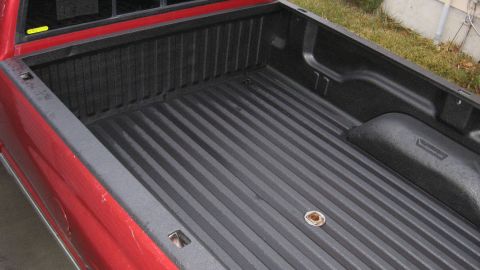 1997 Dodge 2500 - The bed of a red 1997 Dodge 2500 pickup truck features a black spray-in liner and a gooseneck hitch.