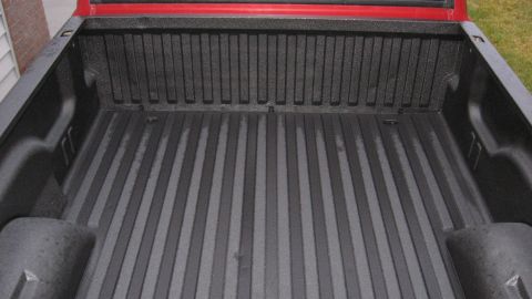 1997 Dodge 2500 - The interior of a truck bed is shown with a black textured liner and visible water droplets.