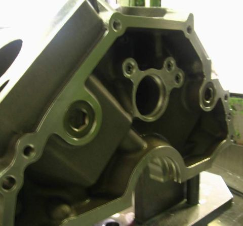 1972 Ford Ranchero - Tight angled close-up of the machined front face of a V8 engine block on a fixture plate, showing the cam bore with its thrust-plate bolt h…