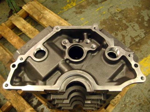 1972 Ford Ranchero - Close-up of the front face of a bare V8 engine block on a wooden pallet, showing the freshly decked timing-cover sealing surface, the cam b…