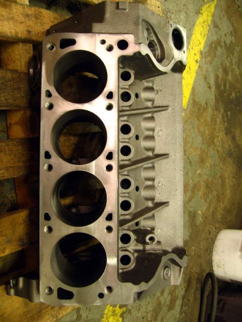 1972 Ford Ranchero - Machined V8 engine block resting on its side on a wood pallet, showing one milled deck surface with four open cylinder bores, head bolt hol…