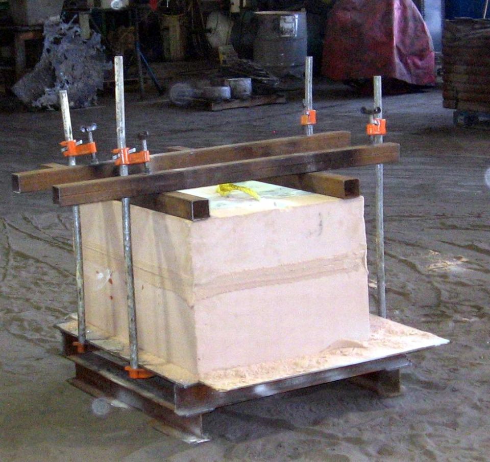 Clamped pink resin sand casting mold set up on a foundry floor ready to pour