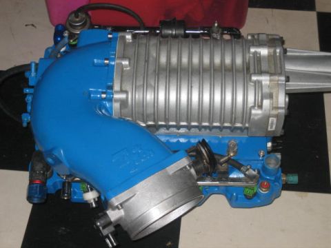 1996 Ford Thunderbird - A blue supercharger assembly with silver components rests on a checkered surface.
