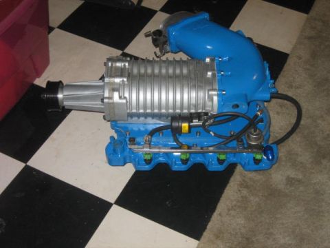1996 Ford Thunderbird - A blue supercharger assembly with silver fins and black hoses is shown on a checkered floor.