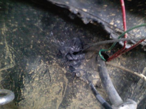 1990 Ford Bronco - Detail of wiring and a hole in a dirty surface, possibly related to an installation. Watermark indicates Supermotors.net.