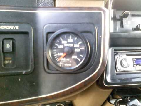 1990 Ford Bronco - A close-up of the vehicle's interior dashboard shows a water temperature gauge and an overdrive switch.