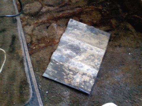 1990 Ford Bronco - A metal plate lies on a dirty floor, likely related to a temporary gauge installation.