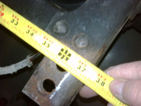 1979 Ford F-250 - A yellow tape measure is used to measure a rusty metal bracket, showing measurements from 33 to 38 inches.
