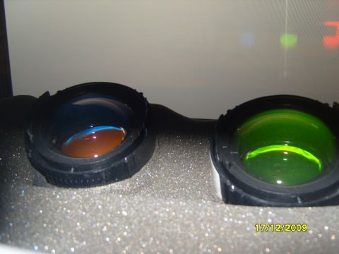 1989 Ford Bronco - Close-up of binocular lenses, one with a blue and brown reflection, the other with a green tint.