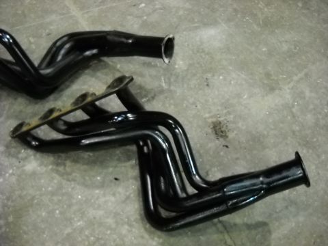 1978 Ford Bronco - Black-painted long-tube header on a concrete floor with its four primary tubes sweeping back into a merge collector and open outlet flange.…