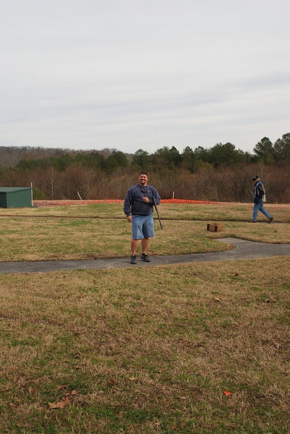 Man holding a rifle at a shooting range with another person in the background