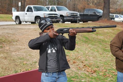1979 Ford F-150 - Several trucks are parked in a lot while a woman aims a shotgun.