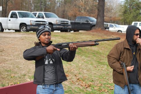 1979 Ford F-150 - Two people with shotguns stand in a grassy area with parked pickup trucks behind them.