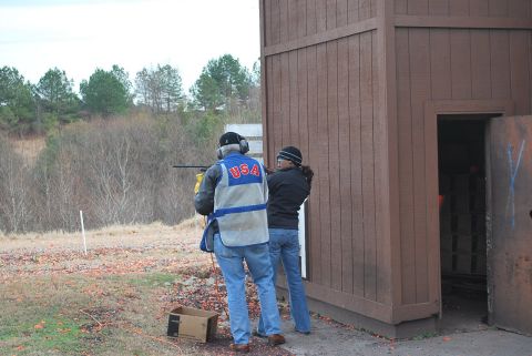 1979 Ford F-150 - Two individuals participate in a shooting activity at an outdoor range, with a wooden shelter and trees visible.