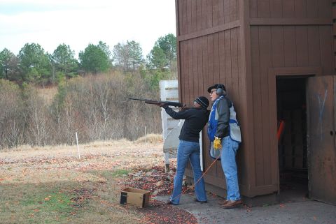 1979 Ford F-150 - A shooting instructor guides a student on aiming a rifle at a clay pigeon shooting range.