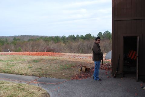 1979 Ford F-150 - A man stands near a building at a shooting range, with broken clay targets visible on the ground.