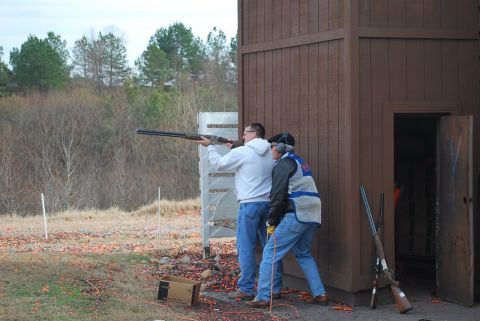 1979 Ford F-150 - Two men participate in a clay pigeon shooting event at an outdoor range.