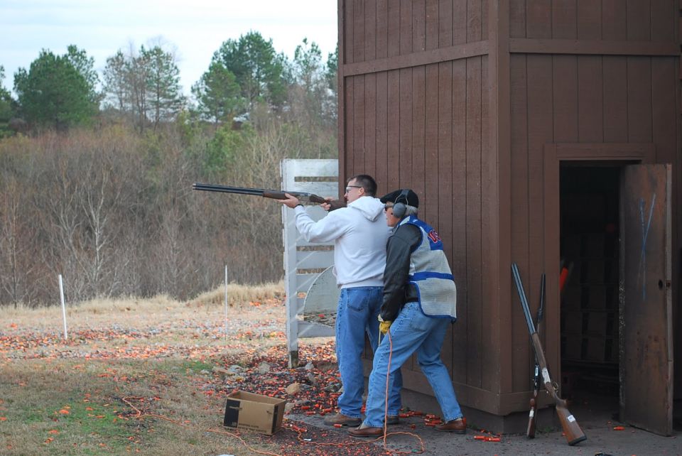 Two men shooting shotguns at a clay pigeon range