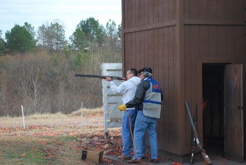 1979 Ford F-150 - Men practice shooting at a clay pigeon range with a wooden structure in the background.