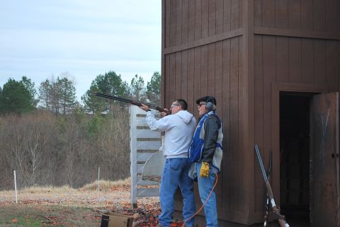 1979 Ford F-150 - Two men are practicing trap shooting at an outdoor range with a wooden structure in the background.