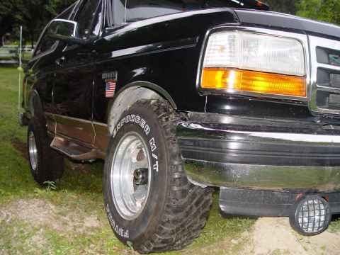 1996 Ford Bronco - A black 1996 Ford Bronco is parked outdoors on a dirt and grass surface.