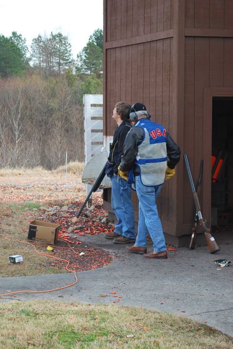 1979 Ford F-150 - Clay pigeon shooting event with participants and shotguns near a wooden structure.