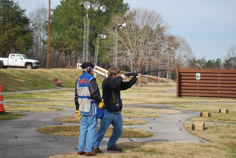1979 Ford F-150 - A white pickup truck is visible in the background at a shooting range where two people are practicing skeet shooting.