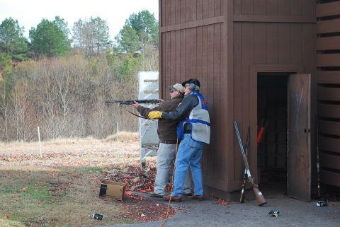 1979 Ford F-150 - An instructor guides a shooter at a clay shooting range, with shotguns visible nearby.