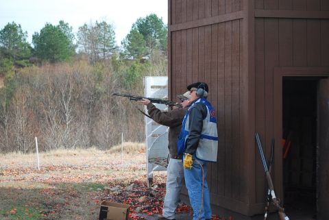 1979 Ford F-150 - Men practice shooting at a clay pigeon range with a wooden structure in the background.